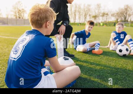 Young Soccer Trainer Coach Erklärt Taktik im Team Sports Tactics Board. Kinder Während Der Fußball-Coaching-Sitzung. Jungen in der Liste der Fußballmannschaften Stockfoto