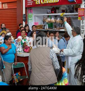 Oaxaca de Juarez, Mexiko. Februar 2020. Fr. Hector Zavala Balboa feiert die Messe auf dem Sanchez Pascuas Nachbarschaftsmarkt an der Dia de la Candelaria und feiert 40 Tage nach der Geburt Jesu. Familien verkleiden Puppen des Baby-Jesus und bringen sie zur Masse, um gesegnet zu werden. Kredit: Jim West/Alamy Live News Stockfoto