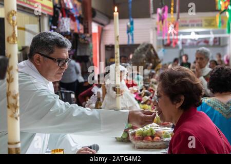 Oaxaca de Juarez, Mexiko. Februar 2020. Fr. Hector Zavala Balboa gibt während der Messe Gemeinschaft auf dem Sanchez Pascuas Nachbarschaftsmarkt an der Dia de la Candelaria. Das Ereignis feiert 40 Tage nach der Geburt Jesu. Familien verkleiden Puppen des Baby-Jesus und bringen sie zur Masse, um gesegnet zu werden. Kredit: Jim West/Alamy Live News Stockfoto