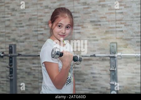 Kleines Mädchen mit Hanteln im Fitnessstudio Stockfoto