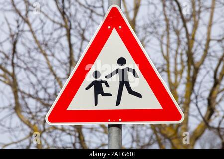 Deutsche Beschilderung Aufmerksamkeit Kinder, die die Straße überqueren, warnen Autofahrer Stockfoto