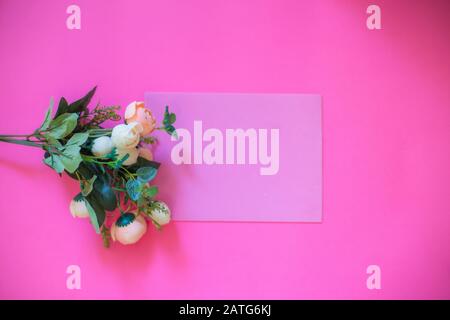 Rahmen aus Rosen auf pinkfarbenem Hintergrund. Flaches Lay. Draufsicht Stockfoto