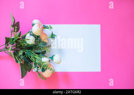 Rahmen aus Rosen auf pinkfarbenem Hintergrund. Flaches Lay. Draufsicht Stockfoto