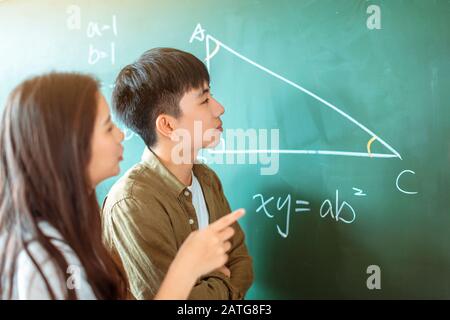 Gruppe von Studenten, die an dem mathematischen Problem im Klassenzimmer arbeiten Stockfoto