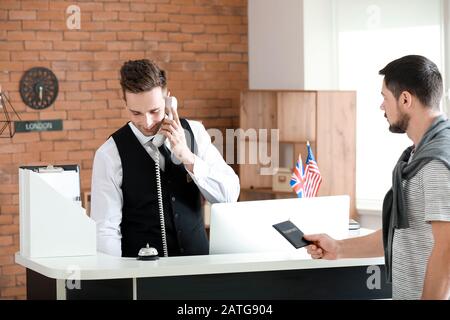 Männliche Mitarbeiter an der Rezeption am Telefon sprechen im Hotel Stockfoto