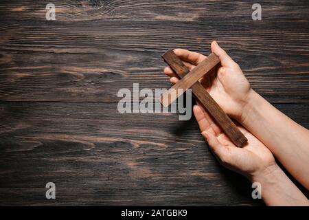 Weibliche Hände mit christenkreuz auf Holzhintergrund Stockfoto