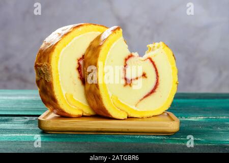 Goldene süße Brötchen und ein Stück mit einem Biss auf einem grünen Tisch Stockfoto