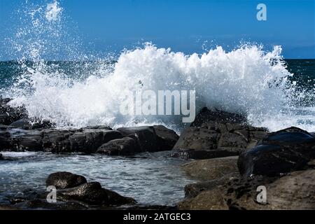 Wellen, die über die Felsen krachen und an einem heißen Sommertag an der Sunshine Coast, Queensland, Australien, einen riesigen Spritzer verursachen. Stockfoto