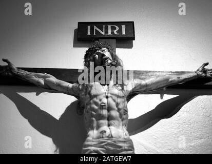 Ein Holzkruzifix an Der Dombasilika St. Franziskus von Assisi in Santa Fe, New Mexico, zeigt Jesus am Kreuz. Stockfoto