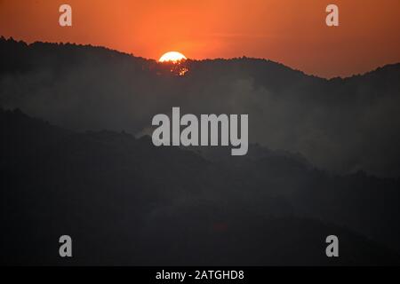 Sonnenaufgang im Doi Pa Hom Pok National Park in Nordthailand, der den Rauch zahlreicher Waldbrände enthüllt Stockfoto