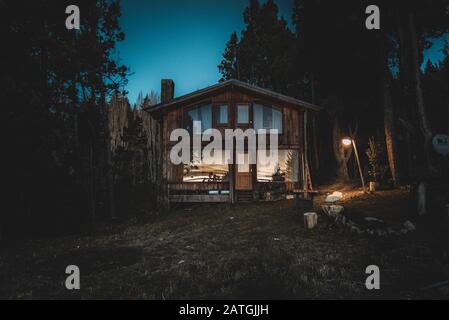 Bariloche, ARGENTINIEN, 19. JUNI 2019: Außenansicht einer gemütlichen und entspannenden Holzhütte im Wald in den letzten Lichtmomenten mit Sonnenuntergang Stockfoto