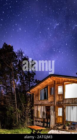 Bariloche, ARGENTINIEN, 19. JUNI 2019: Außenansicht einer gemütlichen und entspannenden Holzhütte im Wald mit einem wundervollen Sternenhimmel Stockfoto