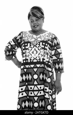 Studioaufnahme einer glücklichen übergewichtigen Afrikanerin lächelnd, während sie mit der Hand auf der Hüfte steht Stockfoto