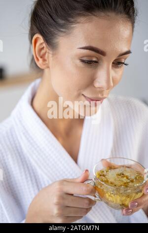 Verträumte Dame, die eine Tasse Kamillentee hält Stockfoto