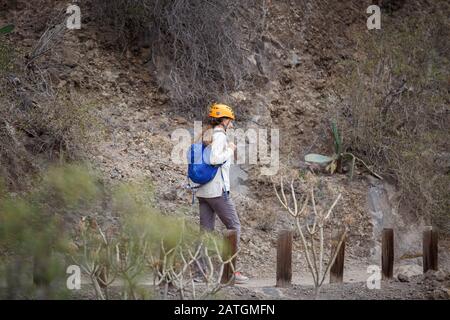 Touristenmädchen mit Helm auf dem Trekkkingpfad in der Schlucht von Tenera, Spanien Stockfoto