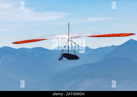 Drachenfliegen gegen die Silhouette der großen Berge in Creston, British Columbia, Kanada. Rasant ansteigender Flug des Drachenfliegers Stockfoto