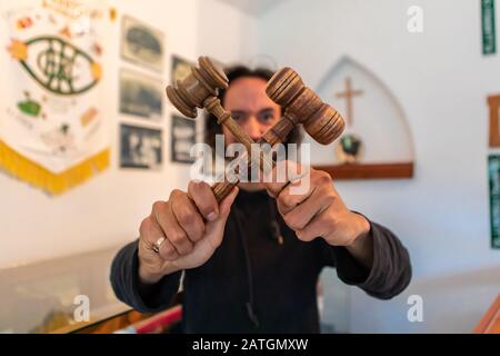 Junger Mann, der zwei Holzhämmer hielt, kreuzte. Die religiöse Person erschreckt die Macht der Dunkelheit. Prediger tritt den Teufel aus. Geh Satan weg Stockfoto