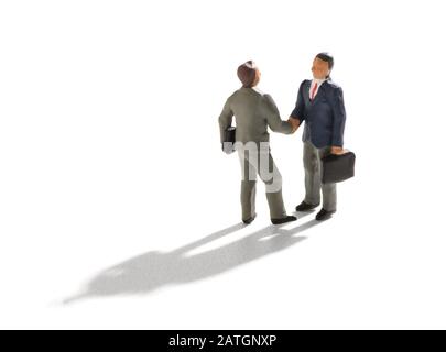 Miniatur-Geschäftsleute schütteln die Hände, isoliert auf weißem Hintergrund mit langem Schatten und aus hohem Blickwinkel betrachtet Stockfoto