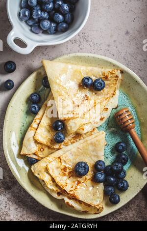 Dünne süße Kreppen-Pfannkuchen mit Blaubeeren und Honig. Stockfoto