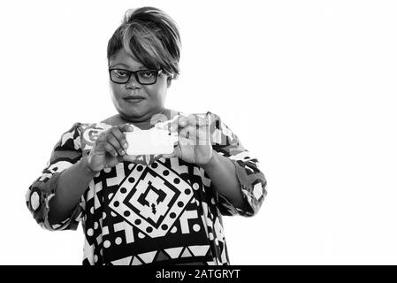 Studioaufnahme von fetter, schwarzer Afrikanerin, die mit dem Handy fotografiert und die Kamera betrachtet Stockfoto