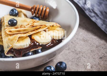 Pfannkuchen mit Schokolade, Früchten und Honig in einem weißen Teller. Stockfoto