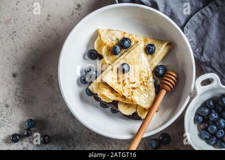 Pfannkuchen mit Schokolade, Früchten und Honig in einem weißen Teller. Stockfoto