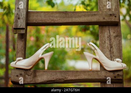 Weiße Hochzeitsschuhe auf einer alten Holztreppe im Garten. Stockfoto