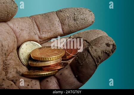 Die schmutzige linke Hand hält einige Euromünzen in ihrer Handfläche. Stockfoto