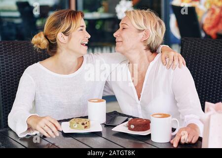 Glückliche Mutter und Tochter genießen gemeinsame Zeit in Kaffeeshop, trinken Kaffee und haben Spaß Stockfoto