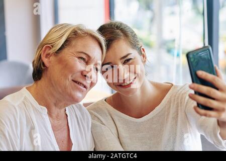 Lächelnde Mutter und Tochter nehmen selfie am Muttertag im Café auf Stockfoto