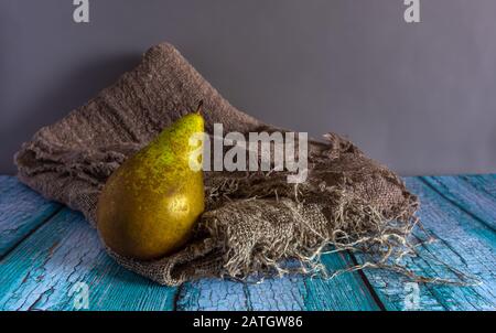 Stillleben mit einer reifen Birne, die auf einem Burlap liegt. Jahrgang. Minimalismus. Es gibt einen Ort für Text. Stockfoto