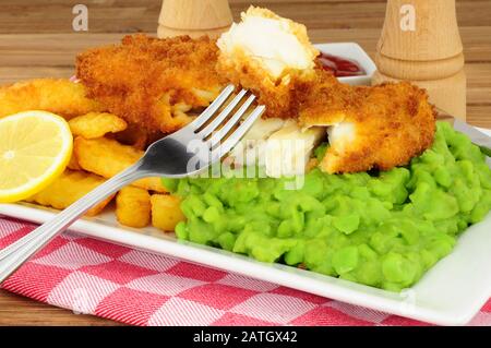 Fisch und Pommes mit matschigen Erbsen Stockfoto