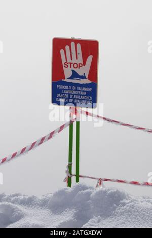 Gefahrenschild - Stopp, Lawinen. Abseits der Piste sonnenbeschienene schneebedeckte Skipiste mit neuem Schnee und übergiebeltem Himmel bei schlechtem Wetter vor blizzard. Stockfoto