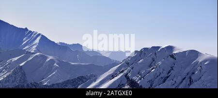 Panoramaaussicht auf schneebedeckte Hochgebirge am frühen Morgen. Kaukasusgebirge. Georgien, Region Gudauri im Winter. Stockfoto