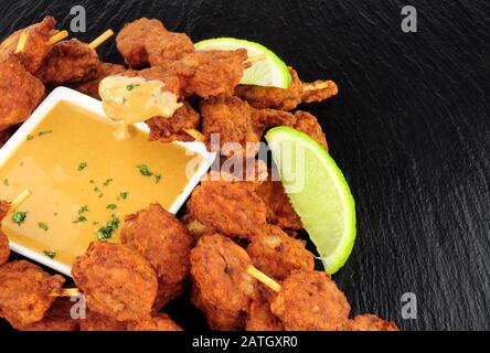 Hähnchensatay-Spieße mit Erdnusssauce tauchen auf einem Schieferhintergrund ein Stockfoto
