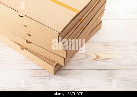 Speisenservice: Pizza wird in braunen Schachteln verpackt, Stapel, Draufsicht auf Holztisch. Stockfoto