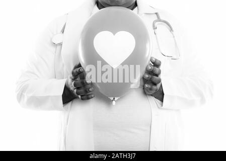 Studio-Schuss von fettschwarzer afrikanischer Frau Doktor hält Ballon mit Herzschild gegen Brust Stockfoto