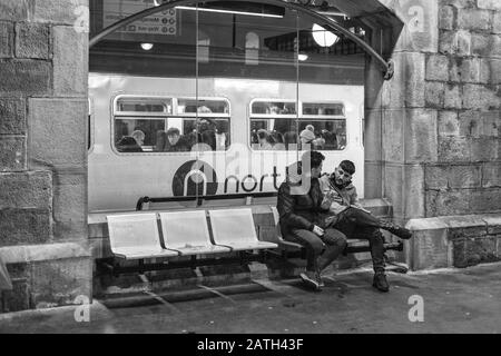 Bahnreisende am Hauptbahnhof von Newcastle mit dem Logo der Northern Rail auf einem dahinter fahrenden Zug Stockfoto