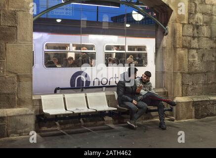 Bahnreisende am Hauptbahnhof von Newcastle mit dem Logo der Northern Rail auf einem dahinter fahrenden Zug Stockfoto