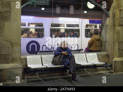 Bahnreisende am Hauptbahnhof von Newcastle mit dem Logo der Northern Rail auf einem dahinter fahrenden Zug Stockfoto