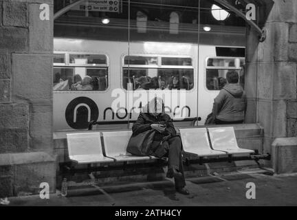 Bahnreisende am Hauptbahnhof von Newcastle mit dem Logo der Northern Rail auf einem dahinter fahrenden Zug Stockfoto