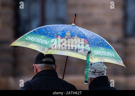 Dresden, Deutschland. Februar 2020. Wenn es regnet, laufen Touristen über den Theaterplatz unter einem Regenschirm, auf dem "die" geschrieben steht. Kredit: Robert Michael / dpa-Zentralbild / dpa / Alamy Live News Stockfoto