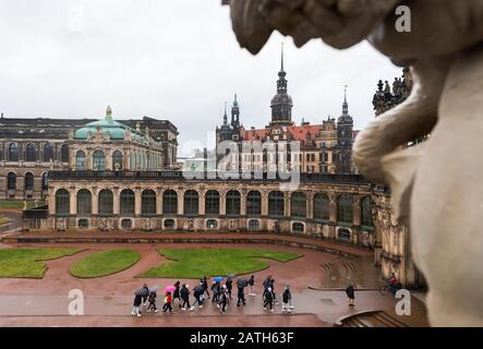 Dresden, Deutschland. Februar 2020. Touristen gehen im Regen durch den Dresdner Zwinger. Im Hintergrund sieht man das Residenzschloss und den Hausmannsturm. Kredit: Robert Michael / dpa-Zentralbild / dpa / Alamy Live News Stockfoto