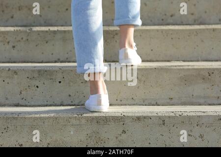 Rückansicht Nahaufnahme der Beine einer Frau, die Turnschuhe trägt, die eine Treppe hoch gehen Stockfoto