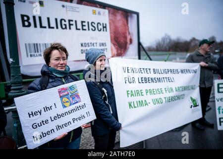 03. Februar 2020, Berlin: Aktivisten der "Arbeitsgemeinschaft bäuerlicher Landwirtschaft" und der Umweltschutzorganisation Greenpeace stehen vor dem Bundeskanzleramt mit einem Protestschild, das "Billiges Fleisch kostet uns die Zukunft" (l-r) und "Verbotene billige Werbung für Lebensmittel" sagt. Im Streit um die Lebensmittelpreise in Supermärkten diskutieren Vertreter des Einzelhandels und der Lebensmittelindustrie bei einem Spitzentreffen mit Kanzlerin Merkel, Landwirtschaftsminister Klöckner und Wirtschaftsminister Altmaier über Lösungen. Foto: Michael Kappeler/d Stockfoto