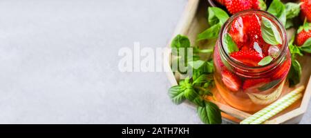 Sommeressen und Getränke. Limonade mit Erdbeere und Basil in Maurerkanne auf Holztablett auf Betontisch. Draufsicht, Kopierbereich Stockfoto