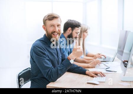 Erfolgreicher Geschäftsmann an seinem Schreibtisch sitzen und mit Blick auf die Kamera Stockfoto
