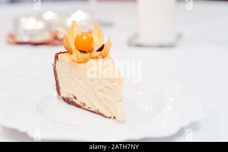 New York Cheesecake garniert mit Physalis auf einem farbigen Hintergrund Stockfoto