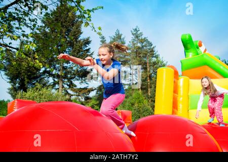 Glückliche kleine Mädchen haben viel Spaß beim Springen von Ball zu Ball auf einem Schloss aufpumpen. Stockfoto