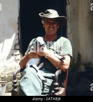 Der deutsche Schauspielleiter Siegfried Rauch bei den Drehararbeiten zu 'Der Stein des Todes' mit einer Ziege in der Hand, Sri Lanka 1986. Der deutsche Schauspieler Siegfried Rauch am Set für 'Dath Stone' mit einer Ziege in den Armen, Sri Lanka 1986. Stockfoto